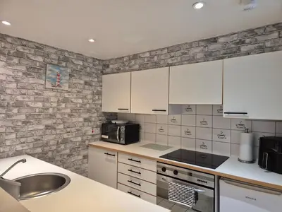 a kitchen with white cabinets and a brick wall at 2 bed GF Docklands Apartment - Free Parking for 1 car in Liverpool