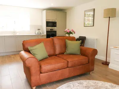 a brown couch with two pillows in a living room at Heron View in Preston