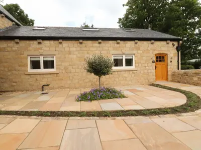 a stone house with a tree in front of it at Heron View in Preston
