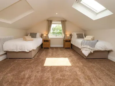 a attic bedroom with two beds and a window at Heron View in Preston