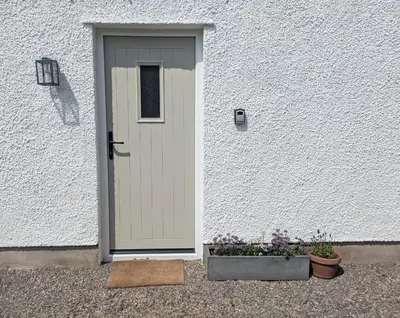 a door in a white building with two potted plants at Field Edge Barn in Silverdale