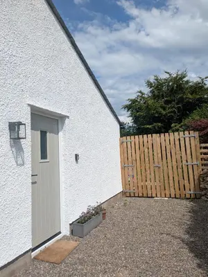 a white house with a door and a wooden fence at Field Edge Barn in Silverdale