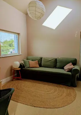 a living room with a green couch and a window at Field Edge Barn in Silverdale
