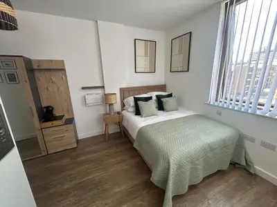 a bedroom with a bed with a green blanket at Central 1-Bed Studio Sleeps 2 with City Views in Liverpool
