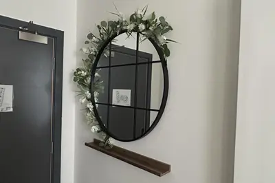 a mirror on a wall with a shelf and flowers at Central 1-Bed Studio Sleeps 2 with City Views in Liverpool