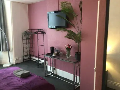 a room with a table with a tv on a pink wall at White Swallow Hotel in Blackpool