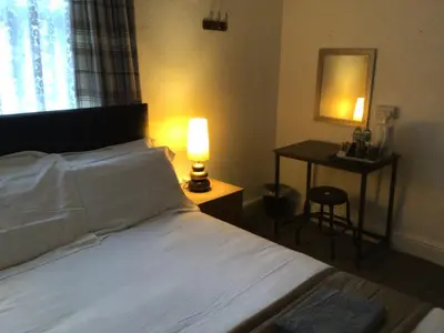 a bedroom with a bed and a table with a lamp at White Swallow Hotel in Blackpool
