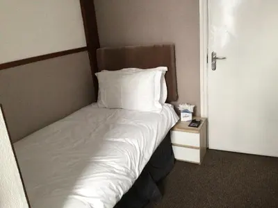 a bed with white sheets and pillows next to a door at White Swallow Hotel in Blackpool