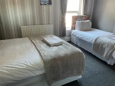 a hotel room with two beds and a chair at Somerville Hotel in Blackpool