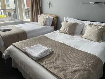 two beds in a room with white sheets and pillows at Somerville Hotel in Blackpool