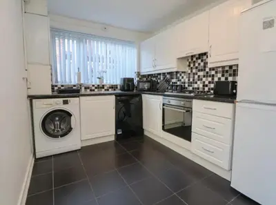 a kitchen with white cabinets and a washer and dryer at Anfield Stadium House - Free Parking in Liverpool