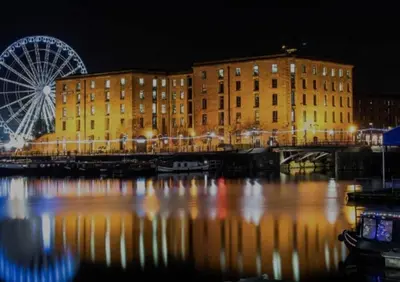 a ferris wheel in front of a building and a river at Anfield Stadium House - Free Parking in Liverpool