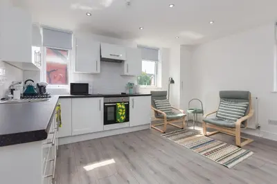 a white kitchen with two chairs and a table at Lytham St Annes Luxury Apartment - No 1 Tides Reach in Lytham St Annes