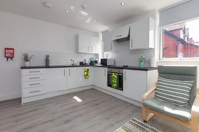 a kitchen with white cabinets and a chair and a window at Lytham St Annes Luxury Apartment - No 1 Tides Reach in Lytham St Annes
