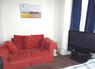 a living room with a red couch and a flat screen tv at Beeton Villas Holiday Apartments in Blackpool