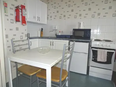a kitchen with a white table and chairs and a microwave at Beeton Villas Holiday Apartments in Blackpool