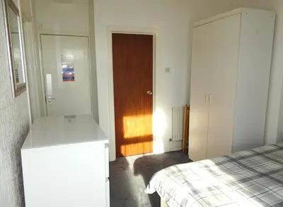 a bedroom with a bed and a wooden door at Beeton Villas Holiday Apartments in Blackpool