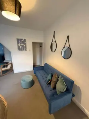 a living room with a blue couch and a blue ottoman at The Wordsworth in Barrow in Furness
