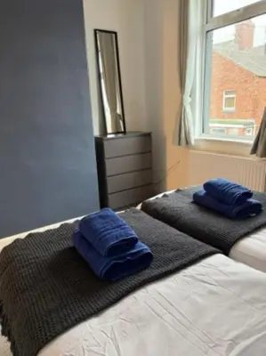 two blue towels are sitting on top of a bed at The Wordsworth in Barrow in Furness