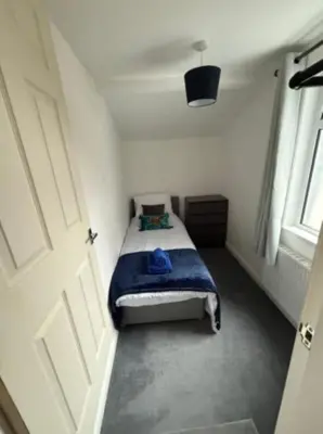 a small bedroom with a bed with a blue blanket at The Wordsworth in Barrow in Furness