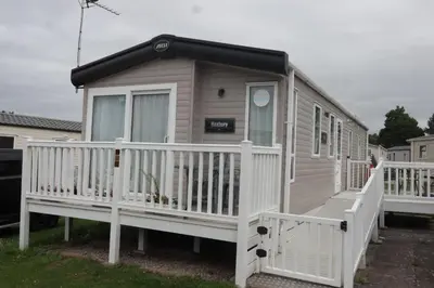 a tiny house with a white railing and a porch at Dennys Holiday Home Pet Free in Blackpool