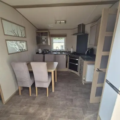 a kitchen with a table and chairs in a tiny house at Dennys Holiday Home Pet Free in Blackpool