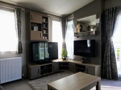 a living room with a desk with a tv and a table at Dennys Holiday Home Pet Free in Blackpool