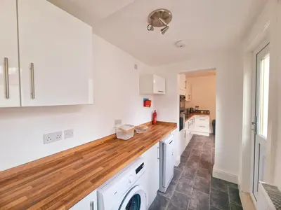 a kitchen with white cabinets and a wooden counter top at Upscale Luxury Home by Liverpool Football Stadium in Liverpool