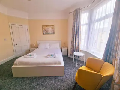 a bedroom with a bed and a chair and windows at Upscale Luxury Home by Liverpool Football Stadium in Liverpool