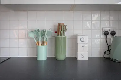 three green vases sitting on a counter with utensils at Lytham St Annes Luxury Apartment - No 3 Tides Reach in Lytham St Annes