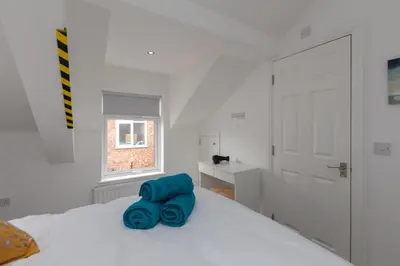 a white bedroom with a white bed with blue sheets at Lytham St Annes Luxury Apartment - No 3 Tides Reach in Lytham St Annes