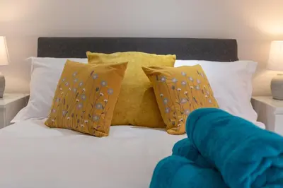a bed with yellow and blue pillows on it at Lytham St Annes Luxury Apartment - No 3 Tides Reach in Lytham St Annes