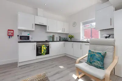 a kitchen with white cabinets and a chair at Lytham St Annes Luxury Apartment - No 3 Tides Reach in Lytham St Annes