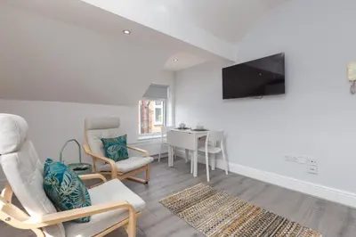 a living room with chairs and a tv and a table at Lytham St Annes Luxury Apartment - No 3 Tides Reach in Lytham St Annes
