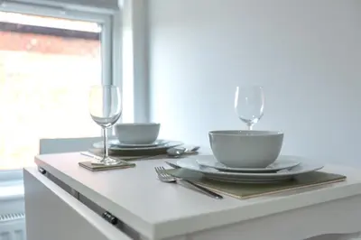 a table with two glasses and a bowl and a plate at Lytham St Annes Luxury Apartment - No 3 Tides Reach in Lytham St Annes