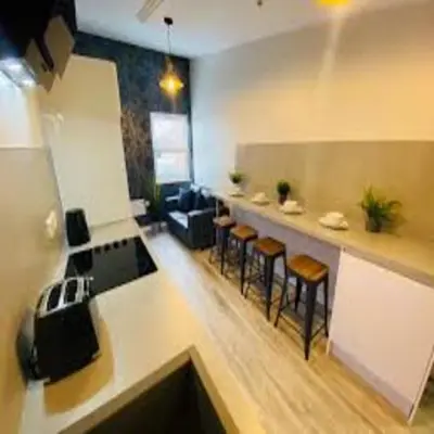 a living room with a kitchen and a bar with stools at Elegant 4-Bedroom Apartment at Kexgill in Preston