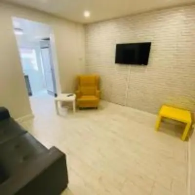a living room with a tv and a yellow chair at Elegant 4-Bedroom Apartment at Kexgill in Preston