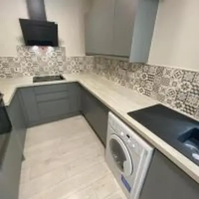 a kitchen with a sink and a washing machine at Elegant 4-Bedroom Apartment at Kexgill in Preston