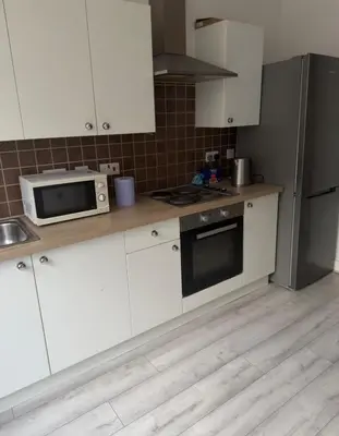a kitchen with white cabinets and a microwave and refrigerator at Central Wigan Stay in Wigan