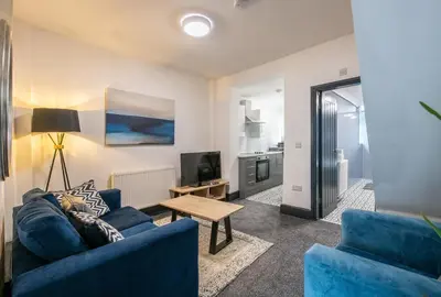 a living room with a blue couch and a table at Prime Location! 3-Bedroom House Near Anfield & Goodison Park in Liverpool