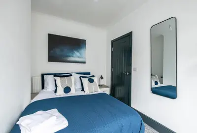 a bedroom with a blue bed and a mirror at Prime Location! 3-Bedroom House Near Anfield & Goodison Park in Liverpool