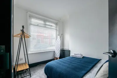 a bedroom with a blue bed and a window at Prime Location! 3-Bedroom House Near Anfield & Goodison Park in Liverpool
