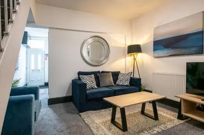 a living room with a blue couch and a table at Prime Location! 3-Bedroom House Near Anfield & Goodison Park in Liverpool