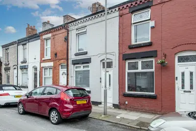 a red car parked on the side of a street at Prime Location! 3-Bedroom House Near Anfield & Goodison Park in Liverpool
