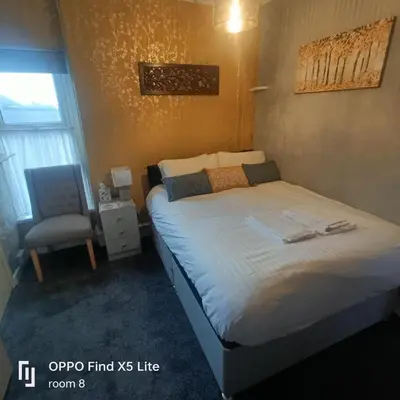 a bedroom with a bed and a chair in it at The Beechwood in Blackpool