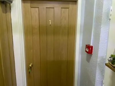 a wooden door in a hallway with a red fire alarm at The Beechwood in Blackpool