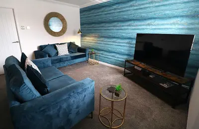 a living room with a blue couch and a television at Lancaster 2 Bedroom House - Driveway Parking in Lancaster