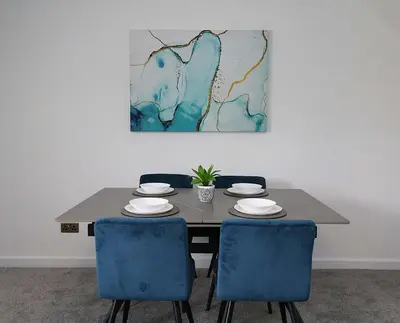 a dining room table with blue chairs and a painting at Lancaster 2 Bedroom House - Driveway Parking in Lancaster