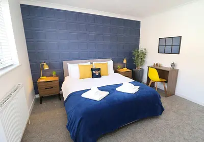 a bedroom with a large bed with a blue wall at Lancaster 2 Bedroom House - Driveway Parking in Lancaster