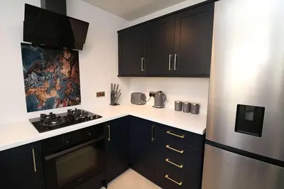 a kitchen with black cabinets and a stainless steel refrigerator at Lancaster 2 Bedroom House - Driveway Parking in Lancaster